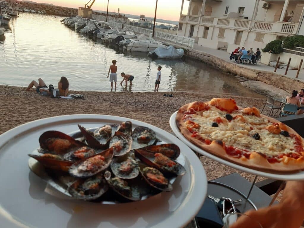 Disfruta de un plato de mejillones gratinados y una pizza provenzal junto al agua en este restaurante de especialidades marsellesas.
