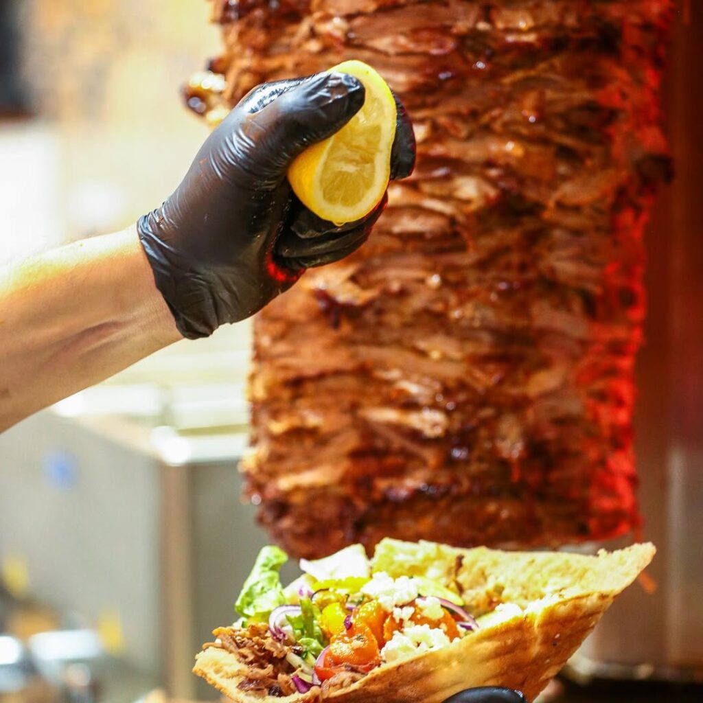 Un asador de kebab con un kebab en salsa de limón en primer plano